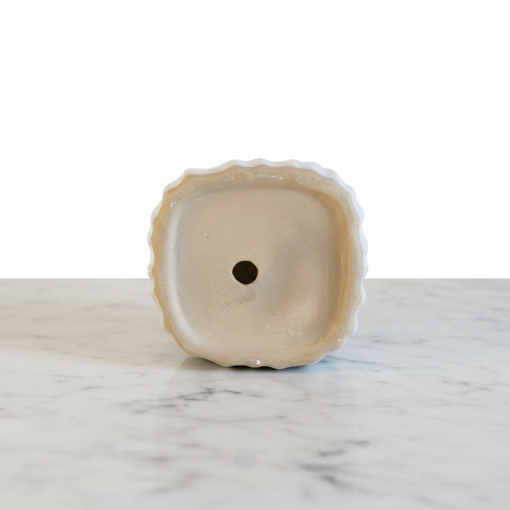 Bottom of ceramic ribbed mini planter showing drainage hole