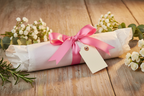 Pink dog harness wrapped as a gift on a wooden table with flowers